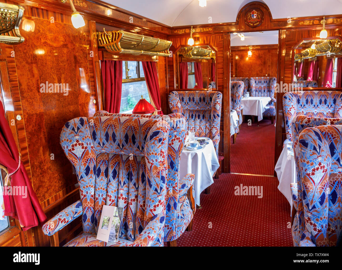 Interior of a panelled dining car Ione with tables set for lunch in the Belmond Venice Simplon Orient Express Stock Photo