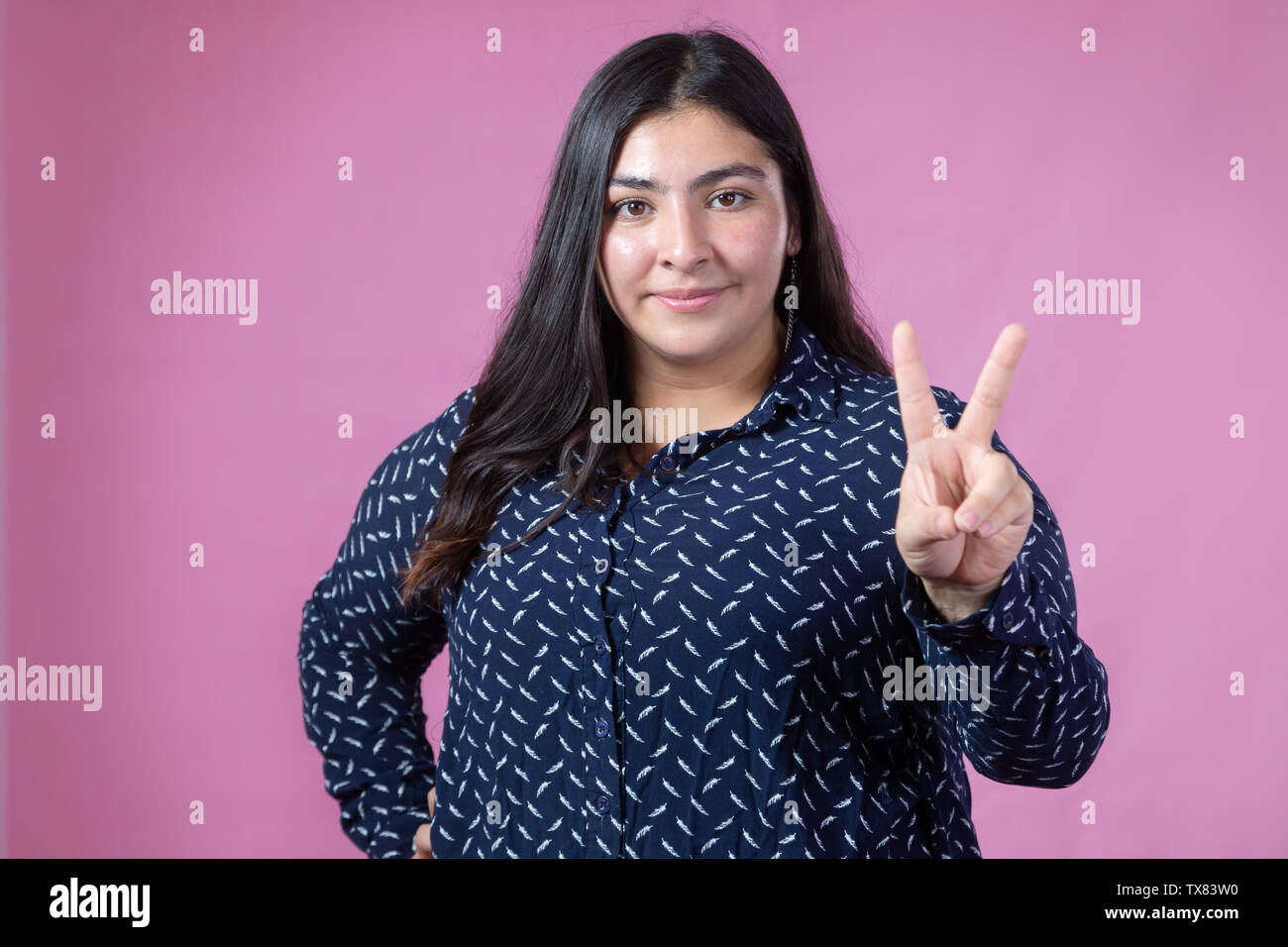pretty curvy girl smiling showing number 2 with fingers or symbol of love and peace Stock Photo