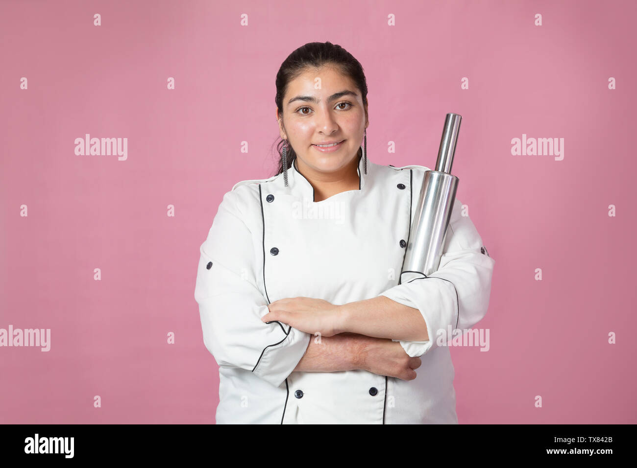 Latin chef with arms crossed and holding his stainless steel roller- woman chef Stock Photo