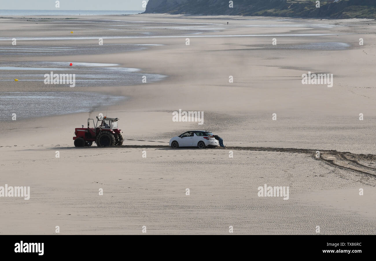 Car stranded on sandy beach at Wissant in northern France being towed by tractor Stock Photo