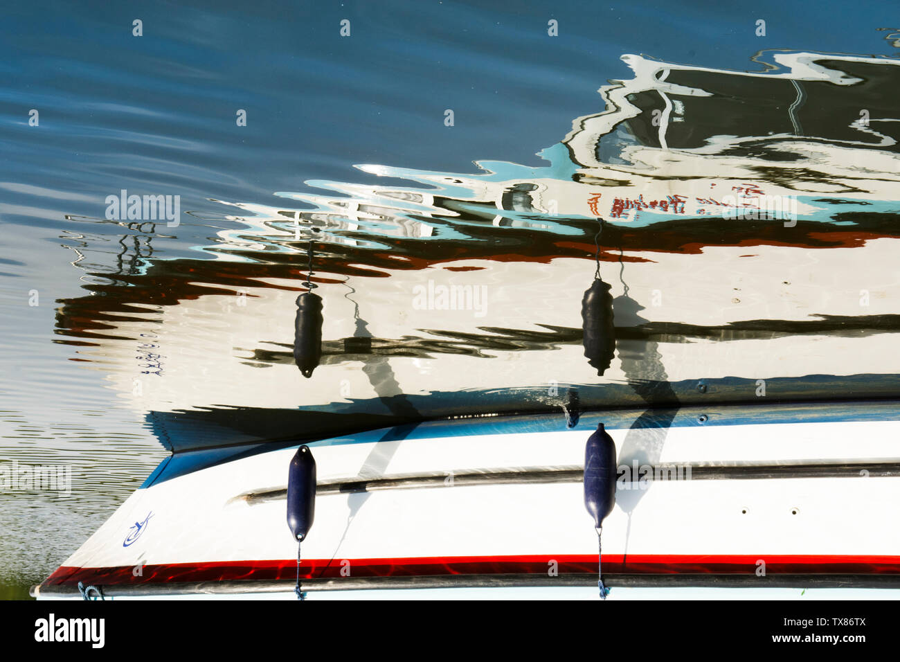 reflection on ripples on water of motor cruiser, boat, holiday boat, the Norfolk Broads, UK, mirror image. Stock Photo