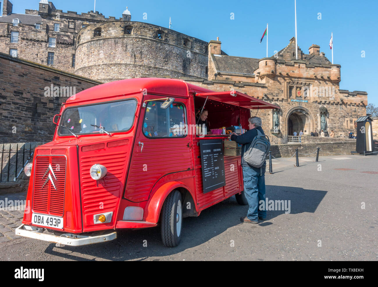 Bright red vintage Citroen H van converted to a food and drink outlet, with a customer being served, parked outside Edinburgh Castle, Scotland, UK. Stock Photo