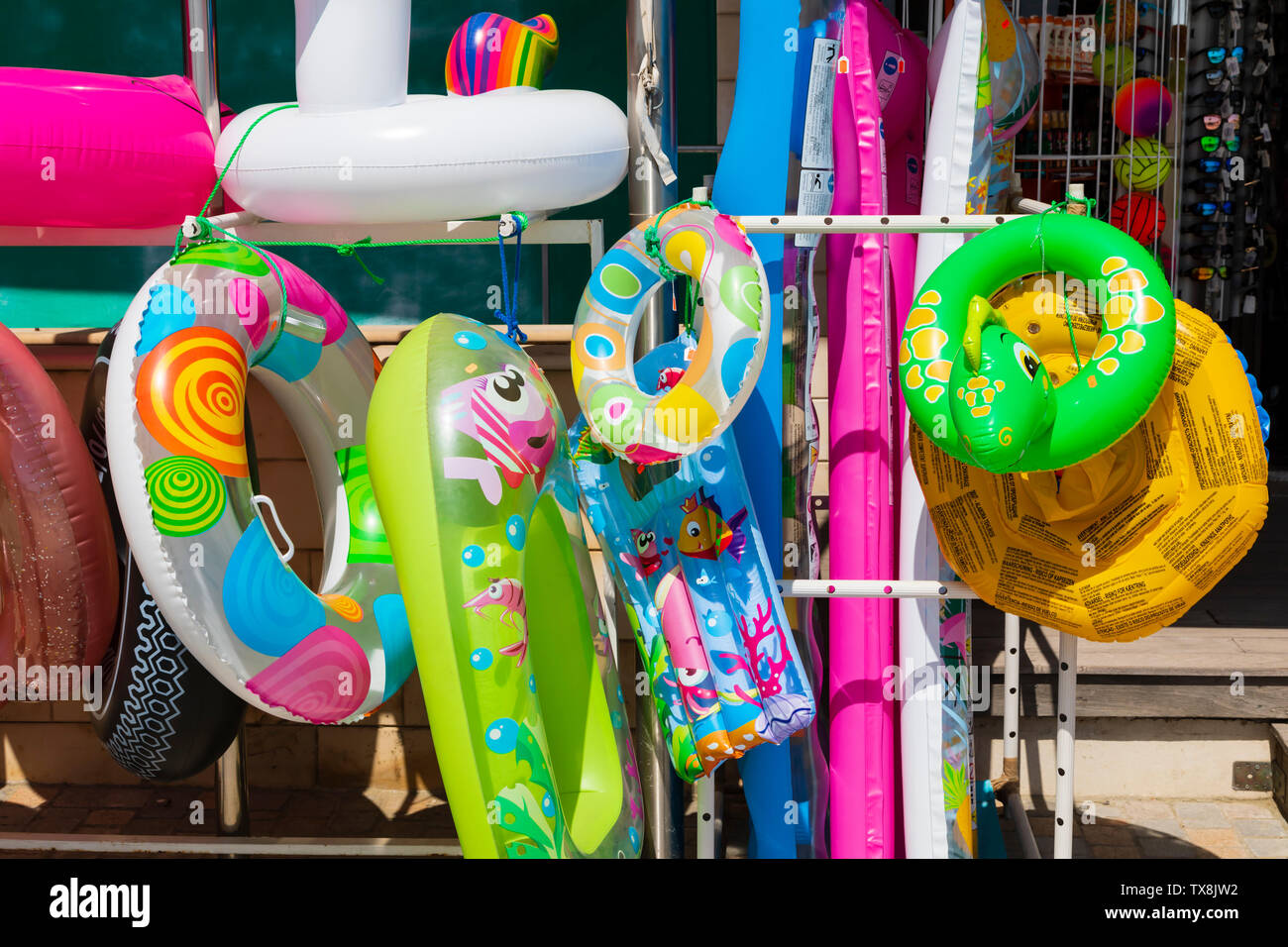 Colourful Inflatable beach toys hanging outside a shop on Finikoudis, Larnaca. Stock Photo