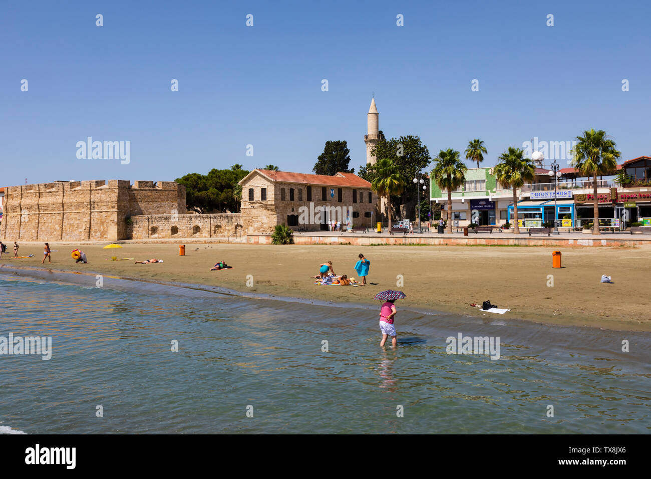 Bathers on the beach at Finikoudis, with the Fort and Mosque in the background. Larnaca, Cyprus. Stock Photo