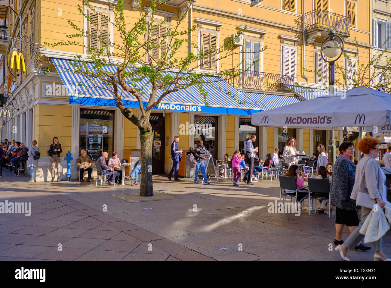 April 19, 2019 : People sitting and enjoying meals purchased at McDonald's restaurant in the city centre square Stock Photo