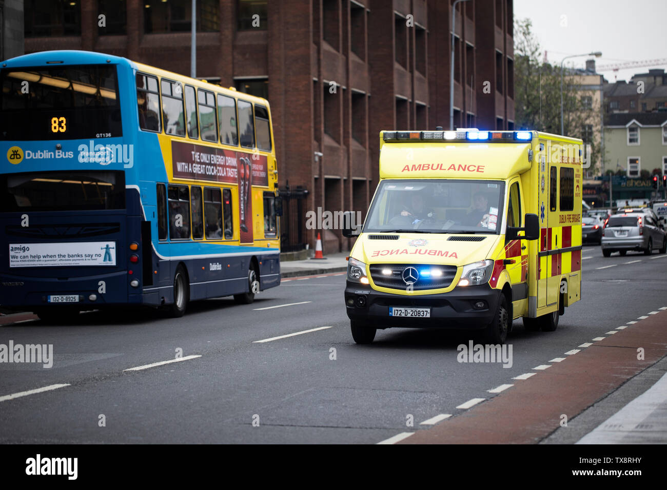 An ambulance with lights flashing races down a busy street in Dublin