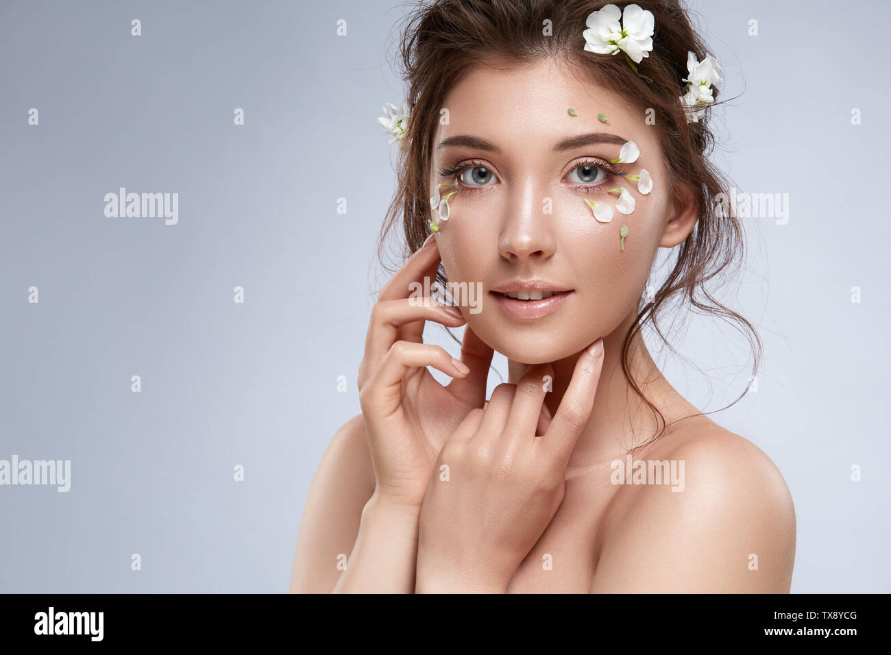 pretty girl with nude make-up and flowers on her face and hair looking to  the camera, sensetivy and flowered beautiful woman Stock Photo - Alamy