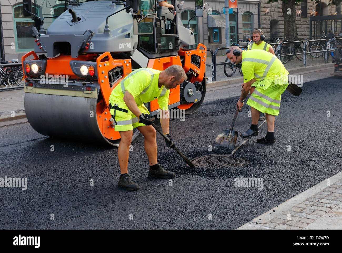 Karlstad, Sweden - June 19, 2019: Road workers asphalting manualy the area around a manhole. Stock Photo