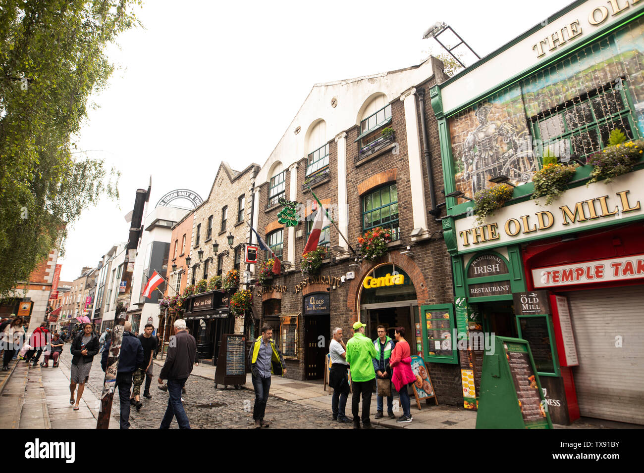 Tourists stroll past the pubs in the Temple Bar district of Dublin, Ireland. Stock Photo