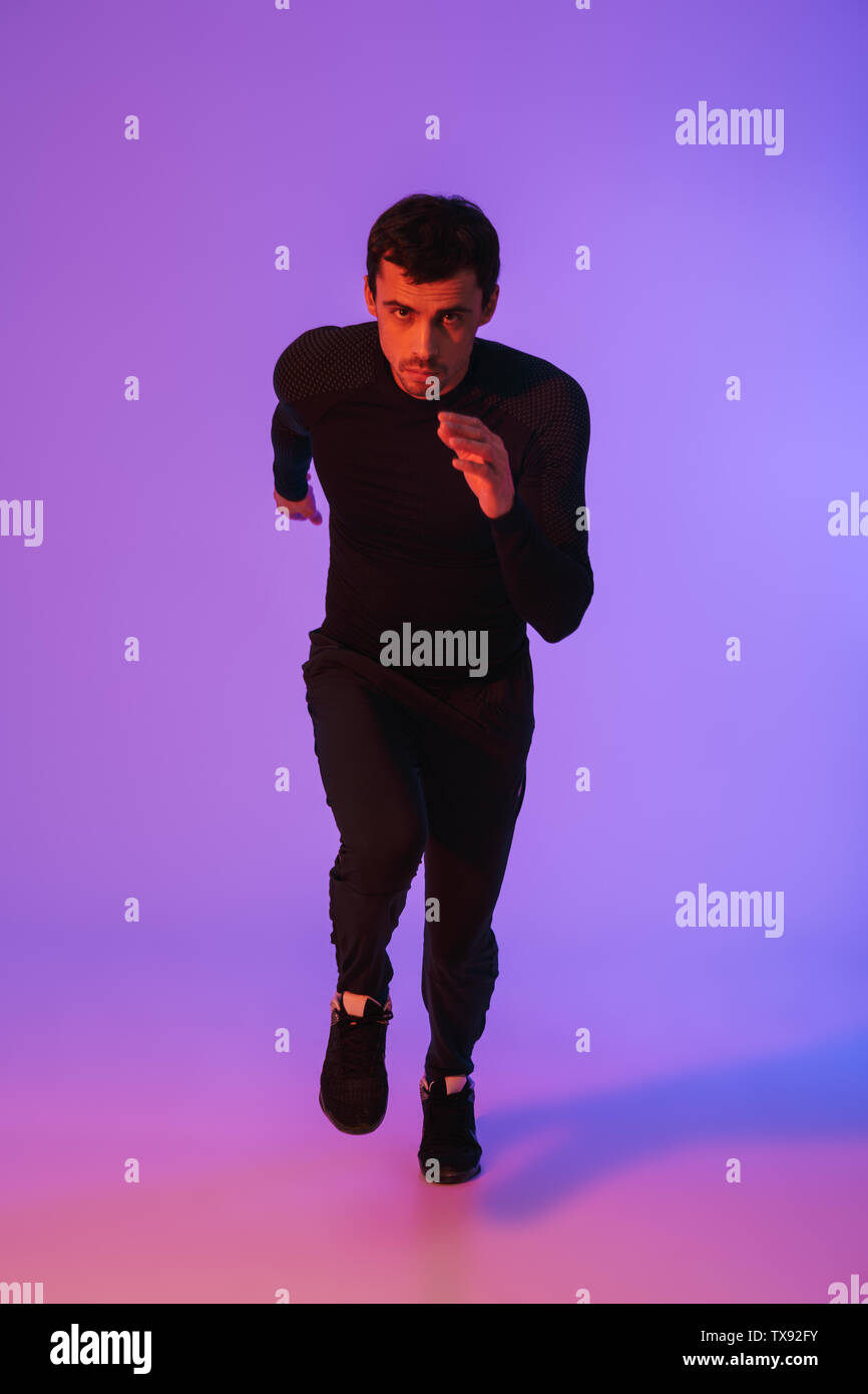 Running Portrait Full length portrait of a fit sportsman running isolated over violet ...