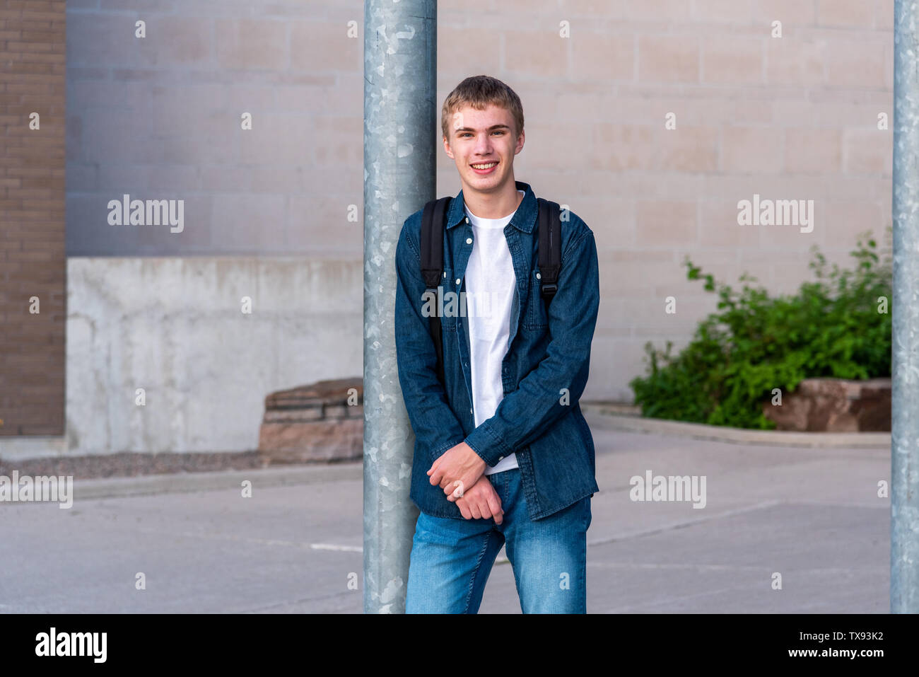 Happy teenager standing in front of the entrance to his high school. Stock Photo