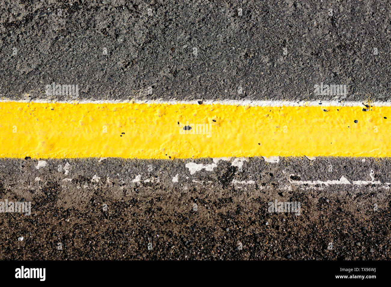 The yellow line is drawn on the asphalt gray tint. The line separates the two parts of the pavement. Stock Photo
