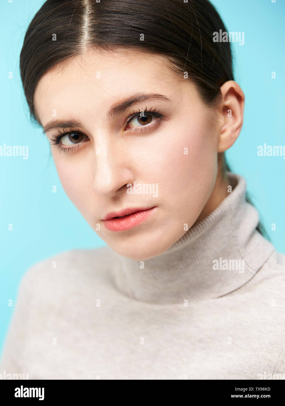 studio portrait of a beautful caucasian woman, looking at camera, isolated on blue background Stock Photo