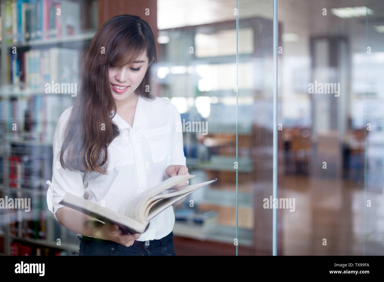 Asian beautiful female student holding book in library Stock Photo - Alamy