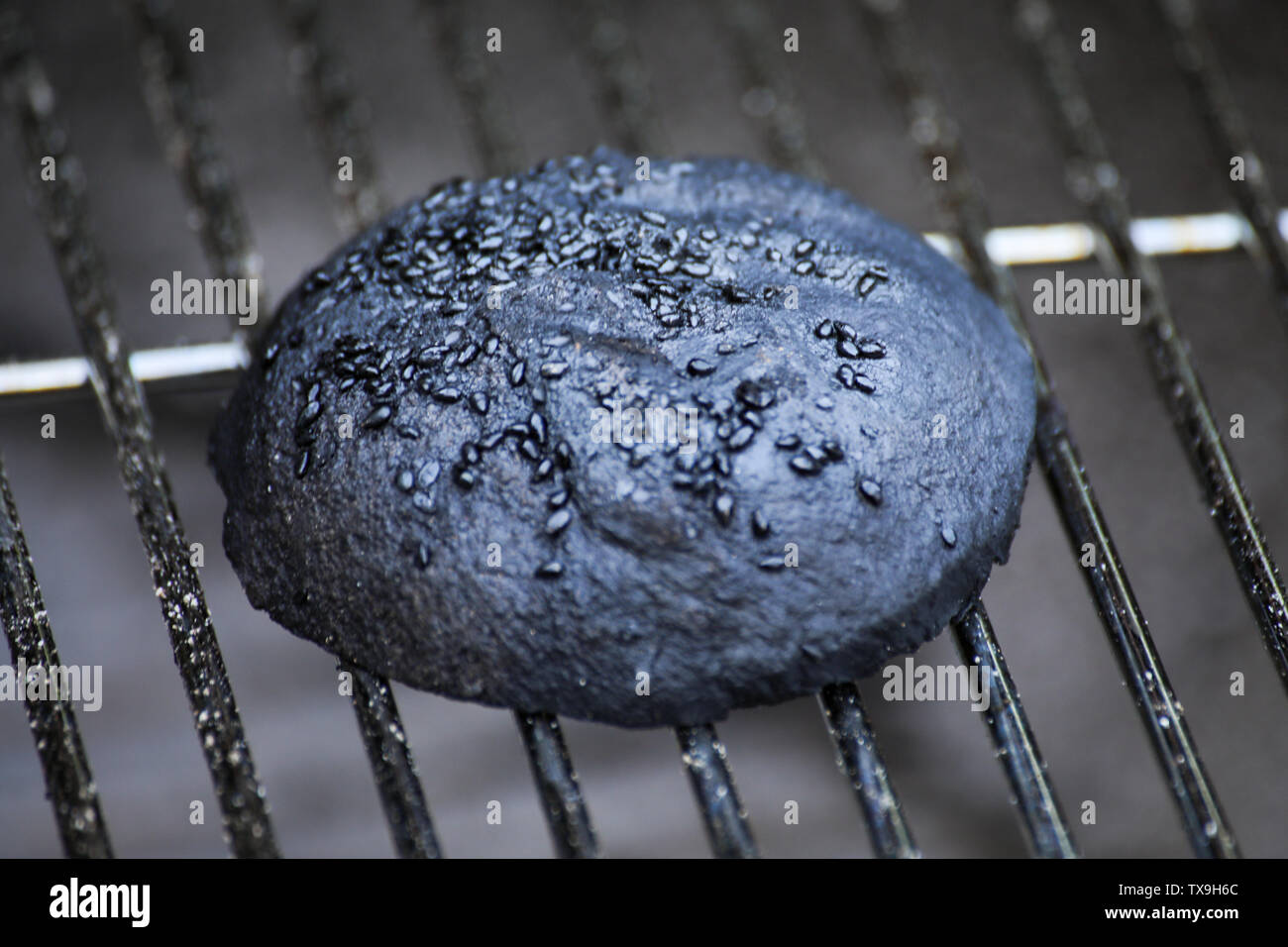 Burnt hamburger bun on grill grid Stock Photo