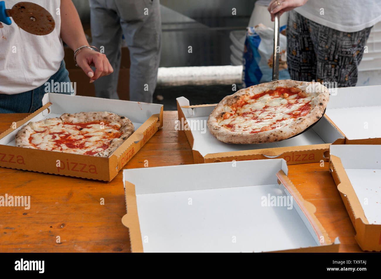 Hot pizza Margherita cut into slices, ready to take-away in cardboard boxes. Stock Photo