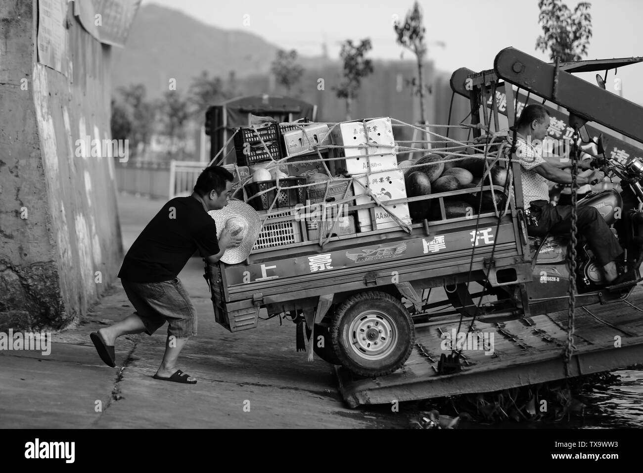 Ferry, a three-wheeled motorcycle full of cargo, the staff are helping to get on the Stock Photo