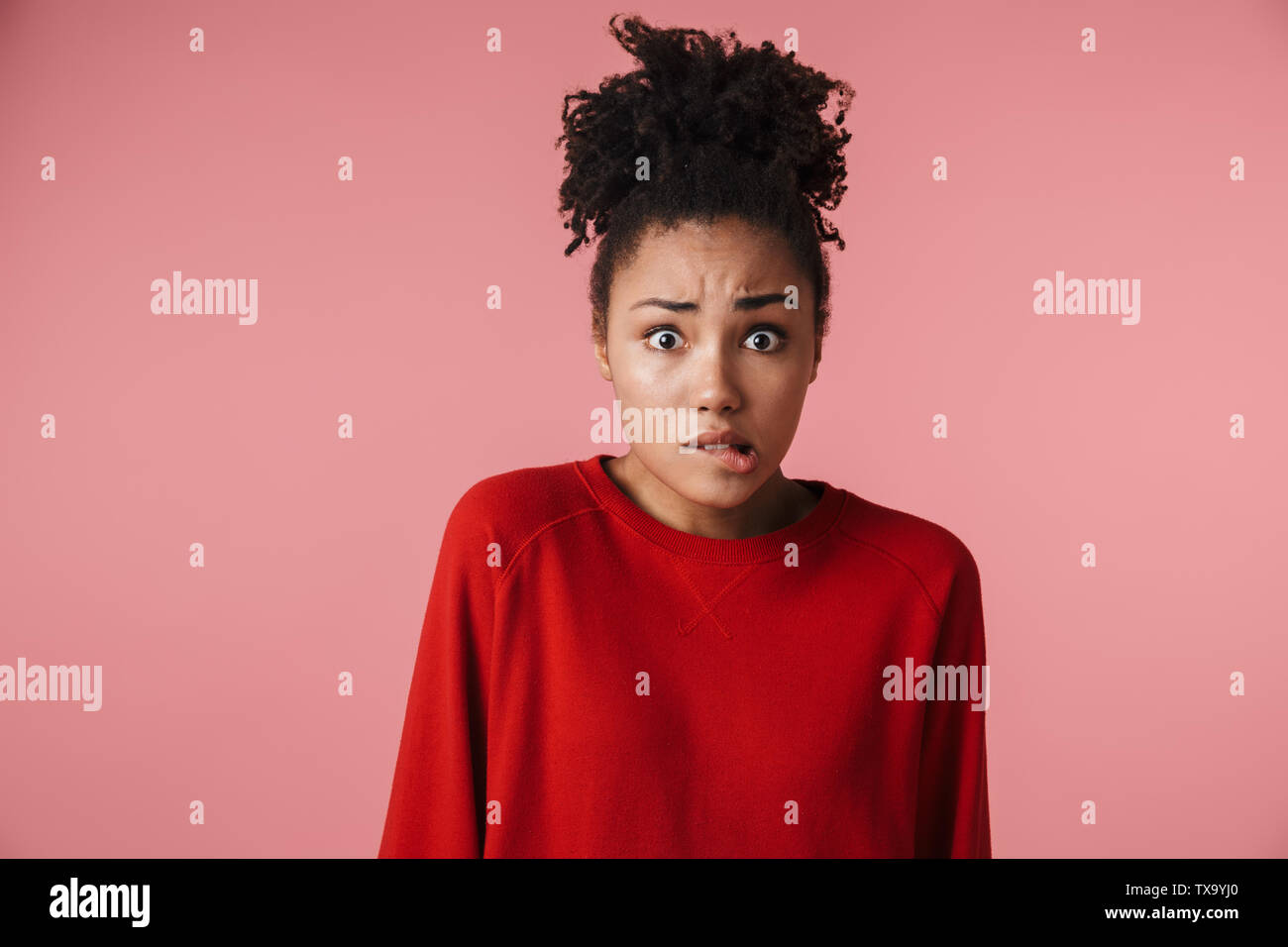 Image closeup of scarred african american woman looking at camera and biting her lip isolated over pink background Stock Photo