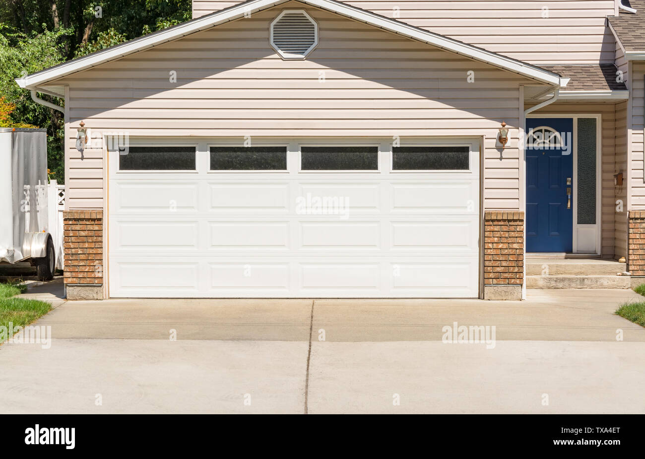 Wide Garage Door Of Residential House And Concrete Driveway In