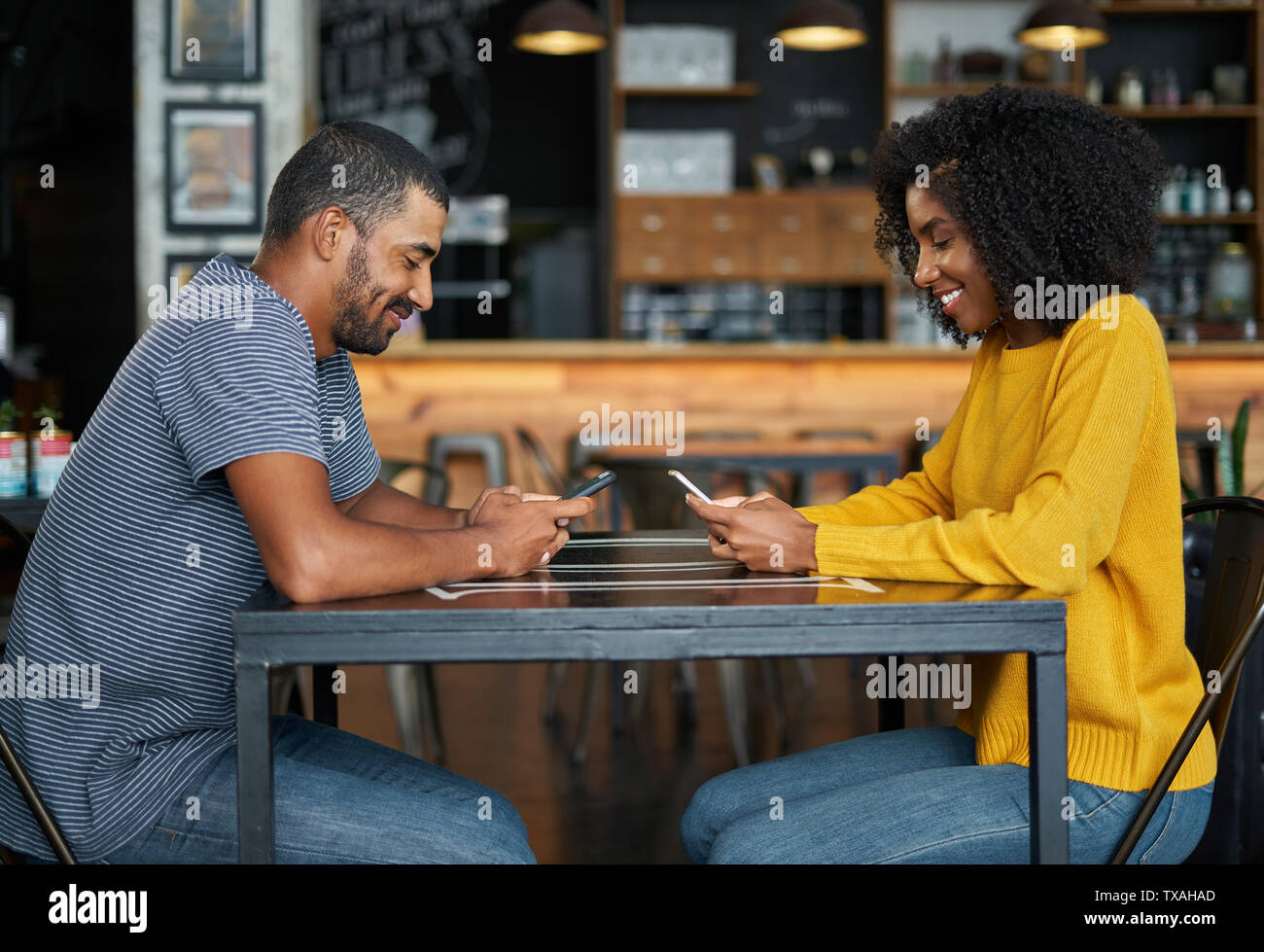 Couple at cafe table using mobile phones Stock Photo