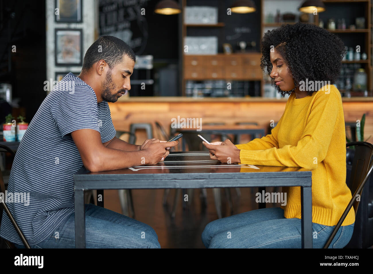 Couple at café table using mobile phones Stock Photo