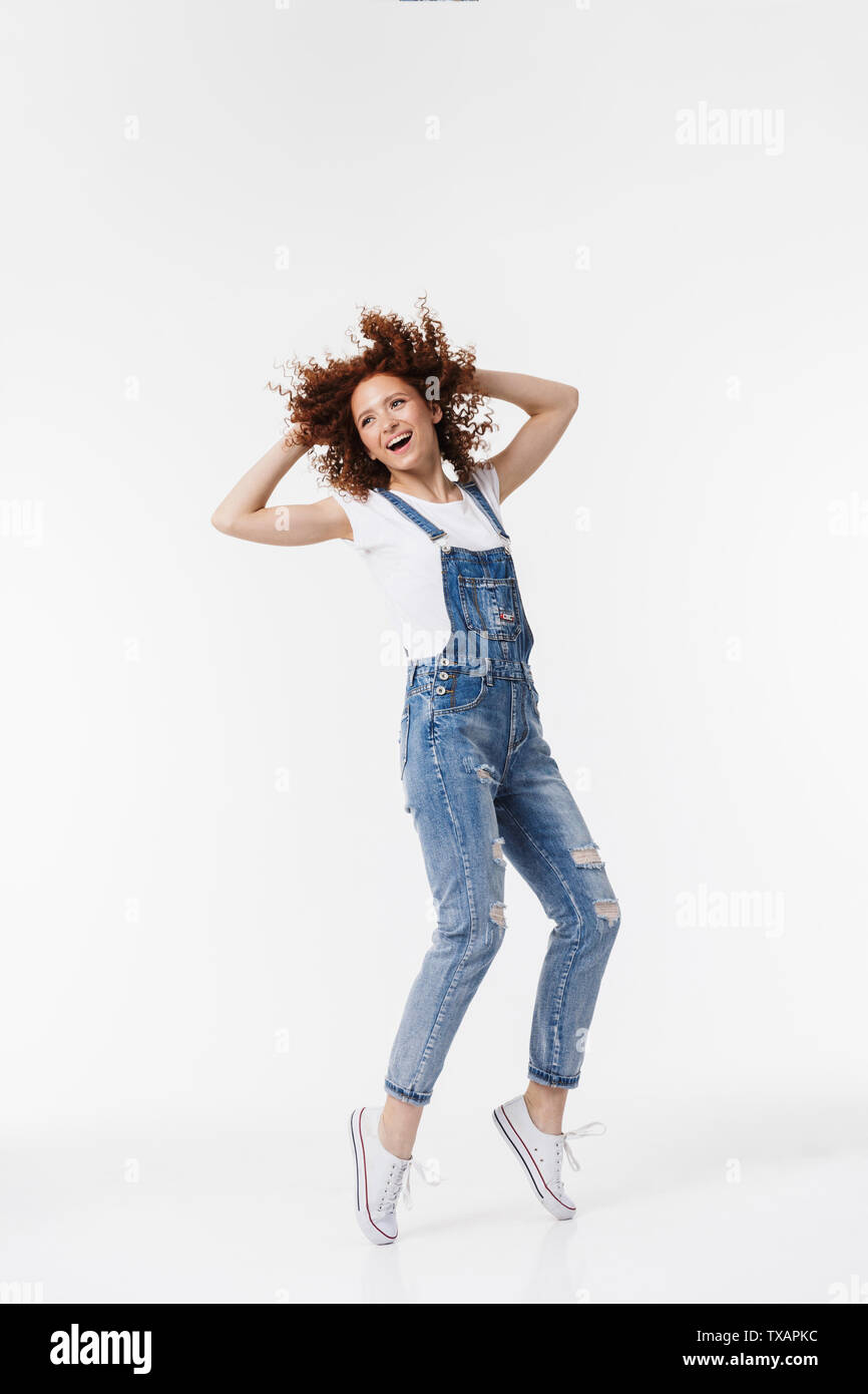 Full length of a cheerful young redhead curly haired girl wearing denim  overalls posing isolated over white background Stock Photo - Alamy