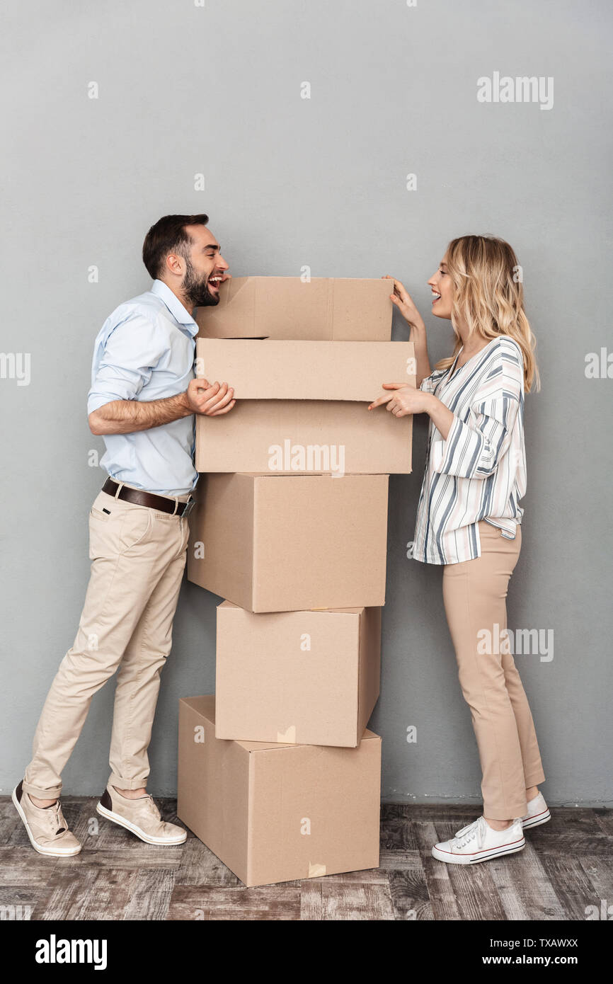Photo of excited laughing couple in casual clothing opening cardboard ...