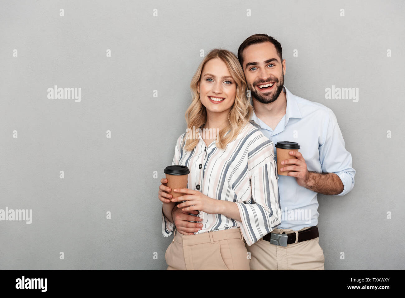 Image of smiling couple in casual clothing holding paper cups and ...