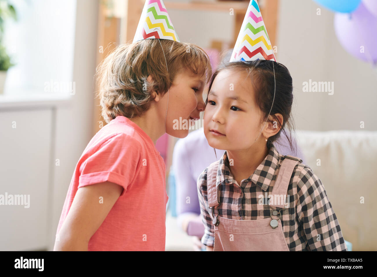 Adorable kids in birthday caps playing childish game Stock Photo