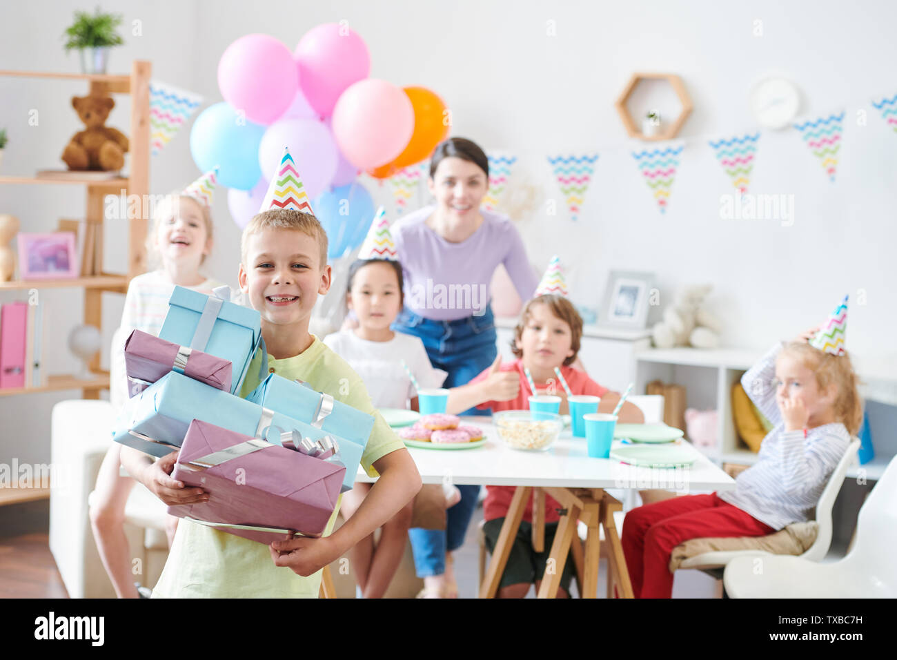 Cheerful little boy with stack of giftboxes standing in front of camera Stock Photo