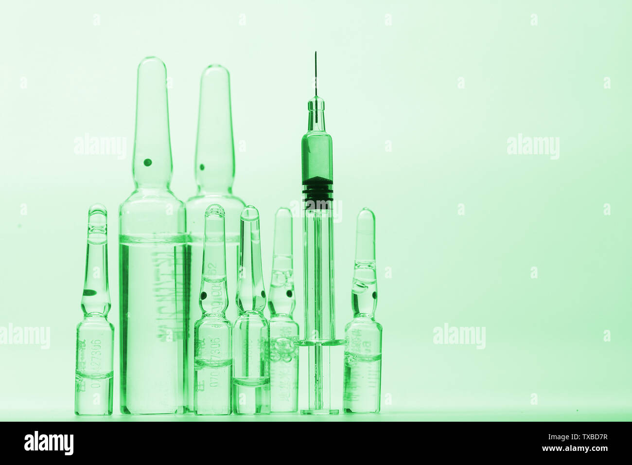 glass syringe in front of medicine bottles in green tone Stock Photo