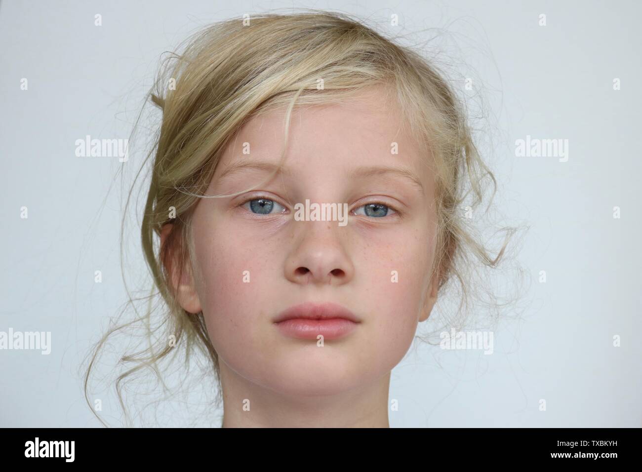 Portrait of a pre adolescent girl staring confidently into the camera against a white background Stock Photo