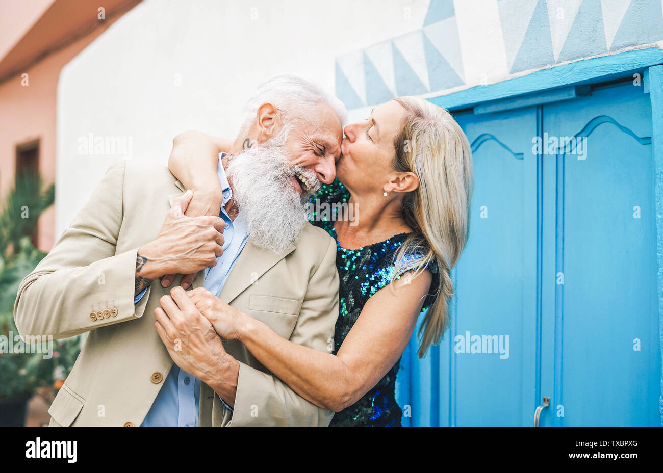 Happy fashion senior couple dating outdoor - Mature elegant older people celebrating date of their anniversary - Wife kissing her husband Stock Photo