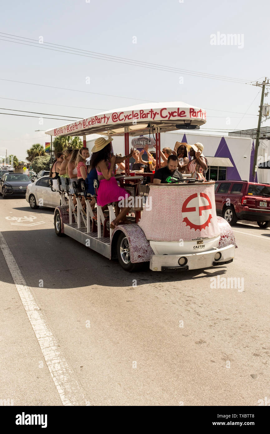 A group of young women pedal a party bike in the daytime in Wynwood, Miami, Florida Stock Photo