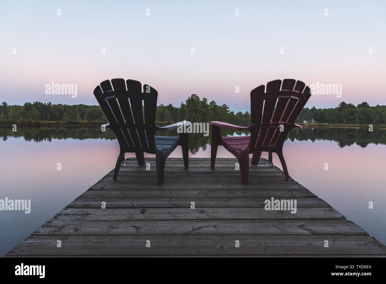 Two Adirondack chairs sitting on a dock Muskoka, Ontario, Canada