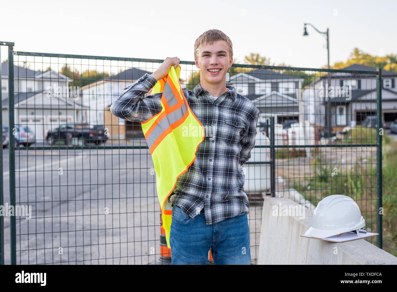 Young construction worker putting on his safety gear at a job site. Stock Photo