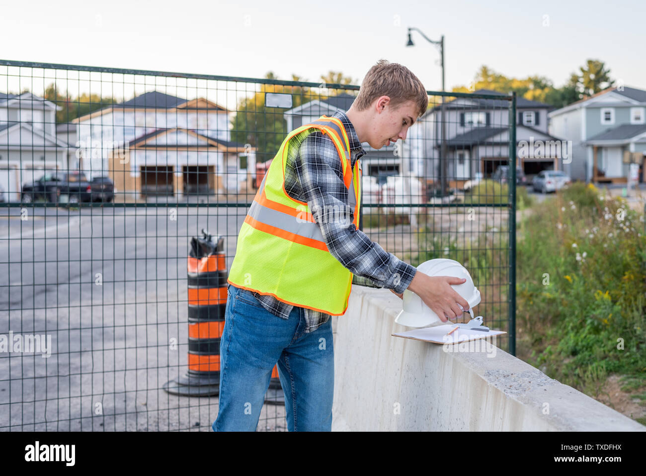 Young construction worker putting on his safety gear at a job site. Stock Photo