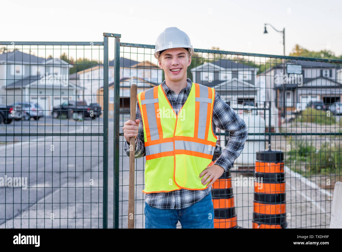 Happy young construction worker standing on a job site and holding a ...