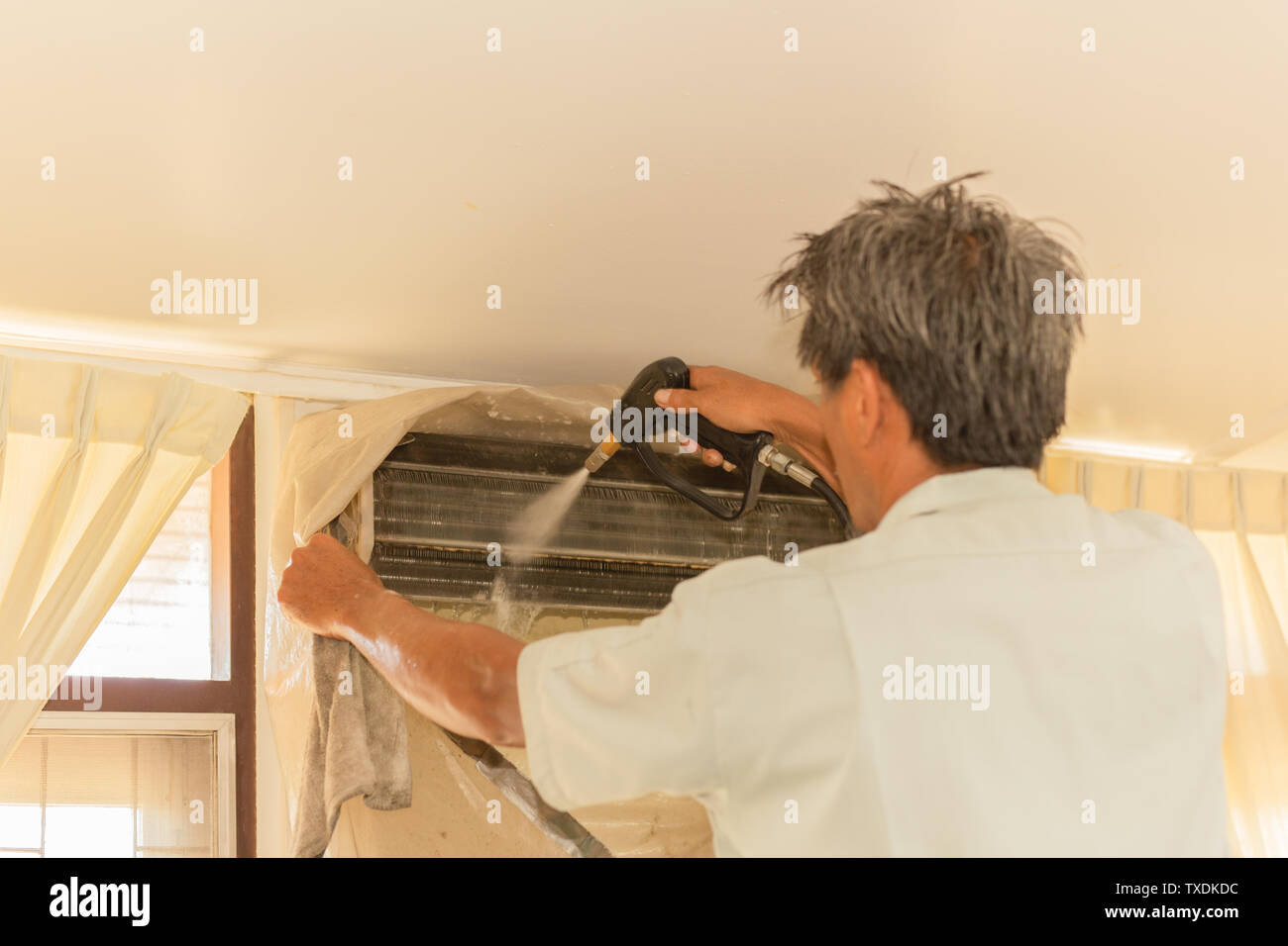 Worker cleaning wall air conditioner with high pressure water jet pump