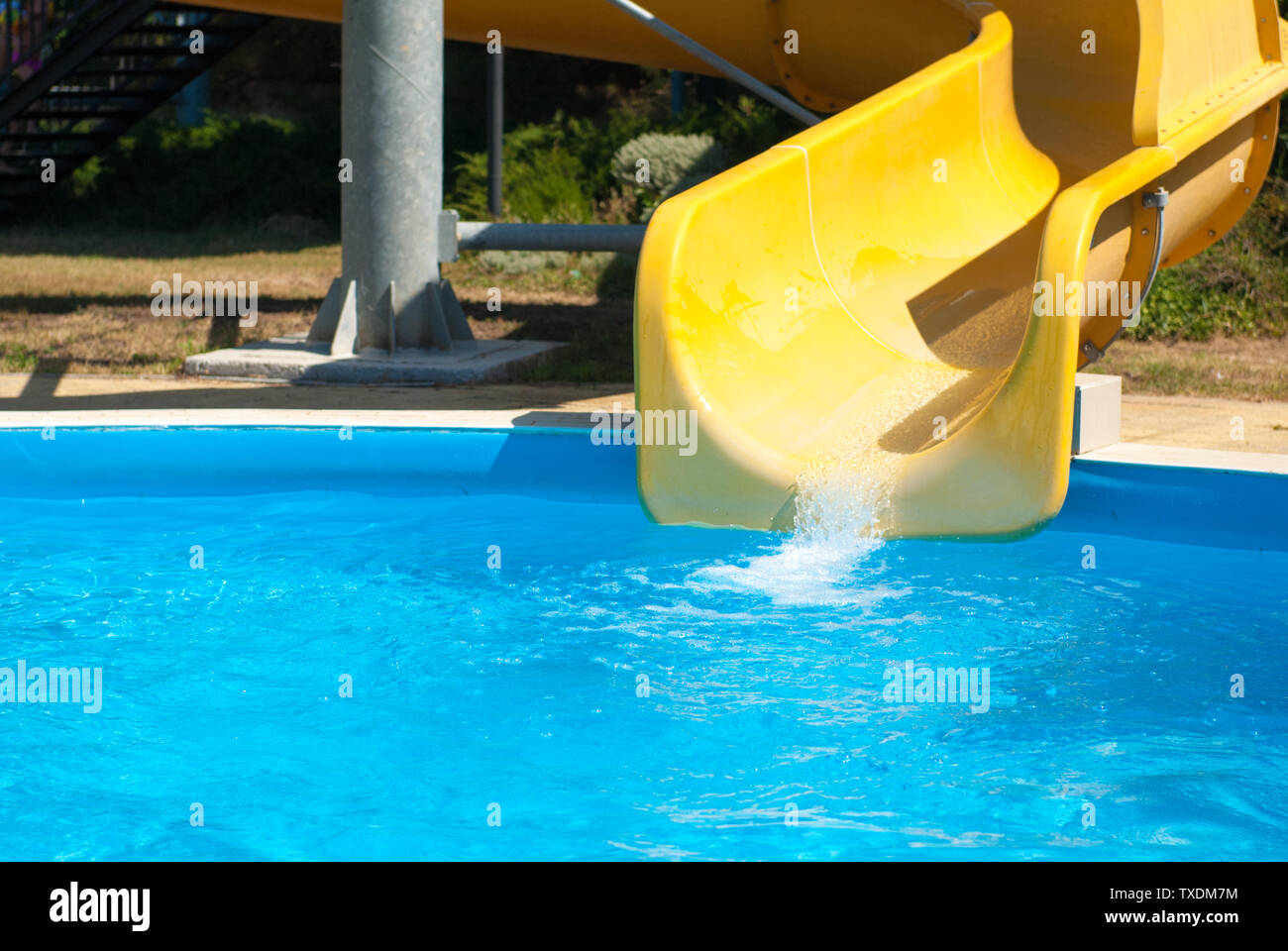 yellow water slide with blue swimming pool in aqua amusement park during summer sunny day Stock Photo