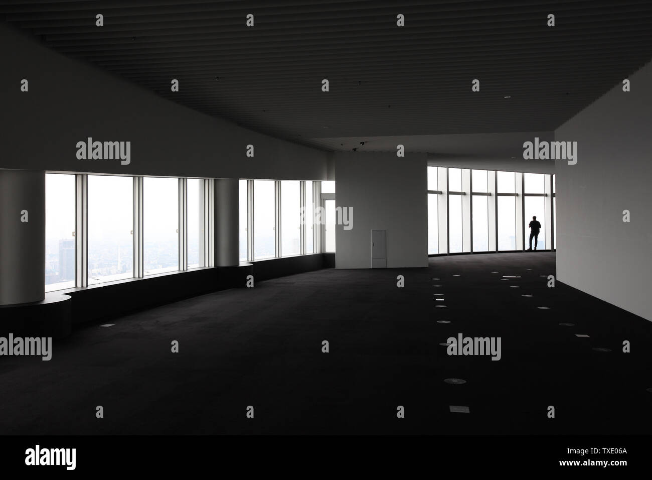 Silhouette of man on a background of a window in an empty room highrise building. Stock Photo