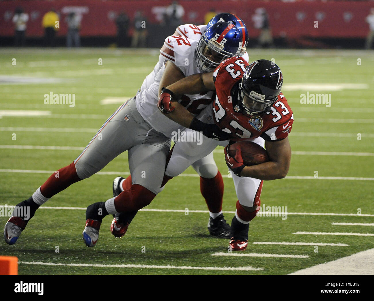 Atlanta Falcons running back Michael Turner 33 is pushed out of bounds by New York Giants outside linebacker Spencer Paysinger 52 in the first quarter of their NFL football game at the