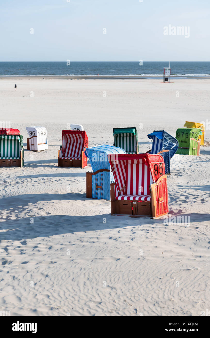 Colorful beach chairs in white sand in the morning on the Frisian