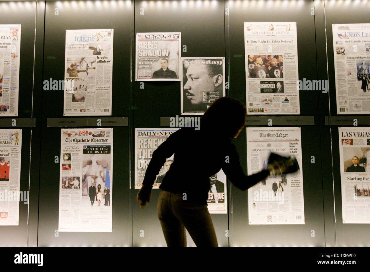 Dora Romero, 31, of Washington, DC cleans the display window at the Newseum in Washington on January 20, 2009, where front pages are displayed from yesterday's papers. Barack Obama is sworn in as the 44th President of the United States today. (UPI Photo/Arianne Teeple) Stock Photo