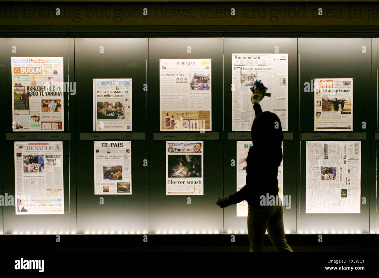 Dora Romero, 31, of Washington, DC cleans the display window at the Newseum in Washington on January 20, 2009, where front pages are displayed from yesterday's papers. Barack Obama is sworn in as the 44th President of the United States today. (UPI Photo/Arianne Teeple) Stock Photo