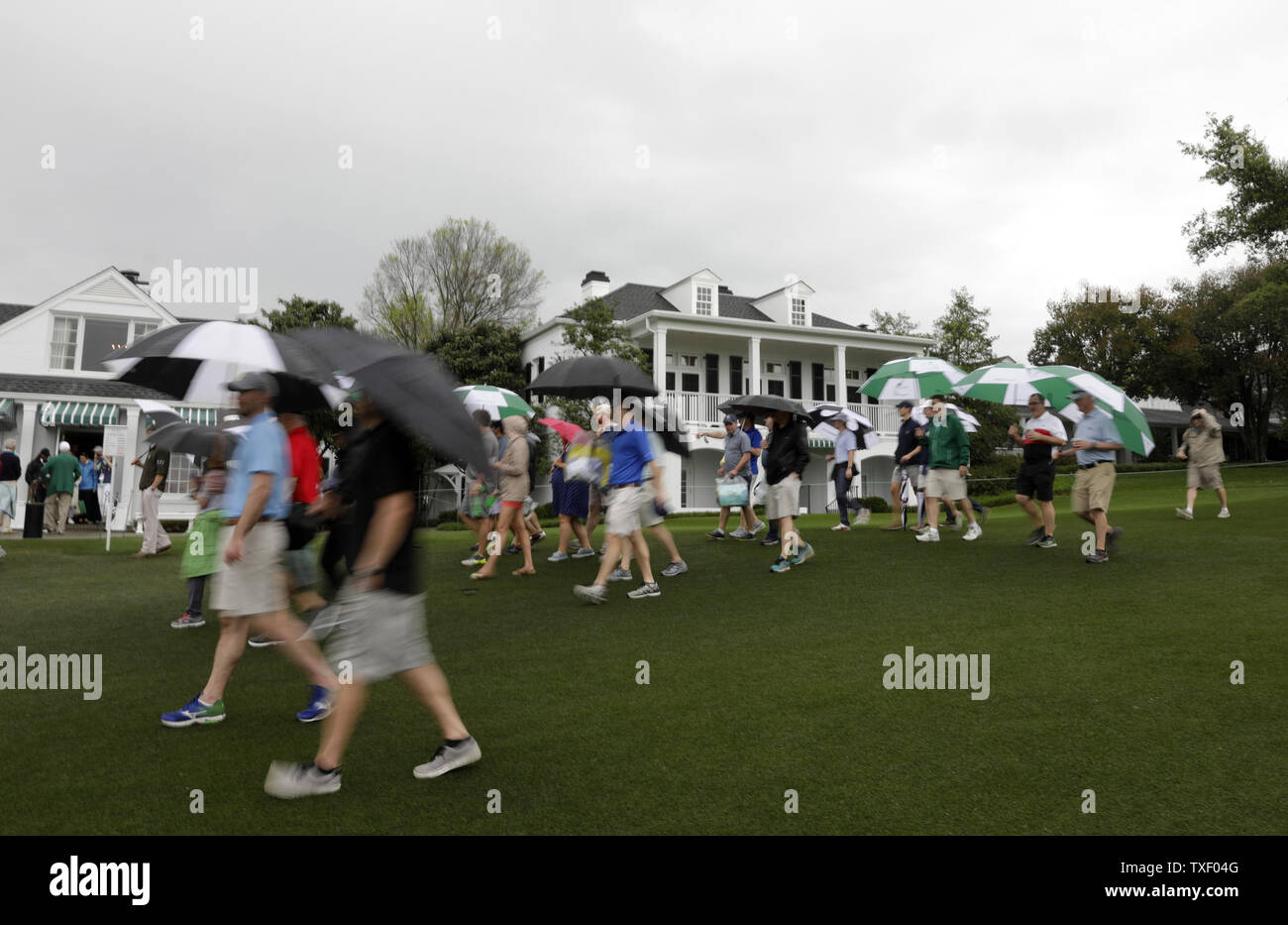 Patrons carrying umbrellas in the rain exit the grounds after the