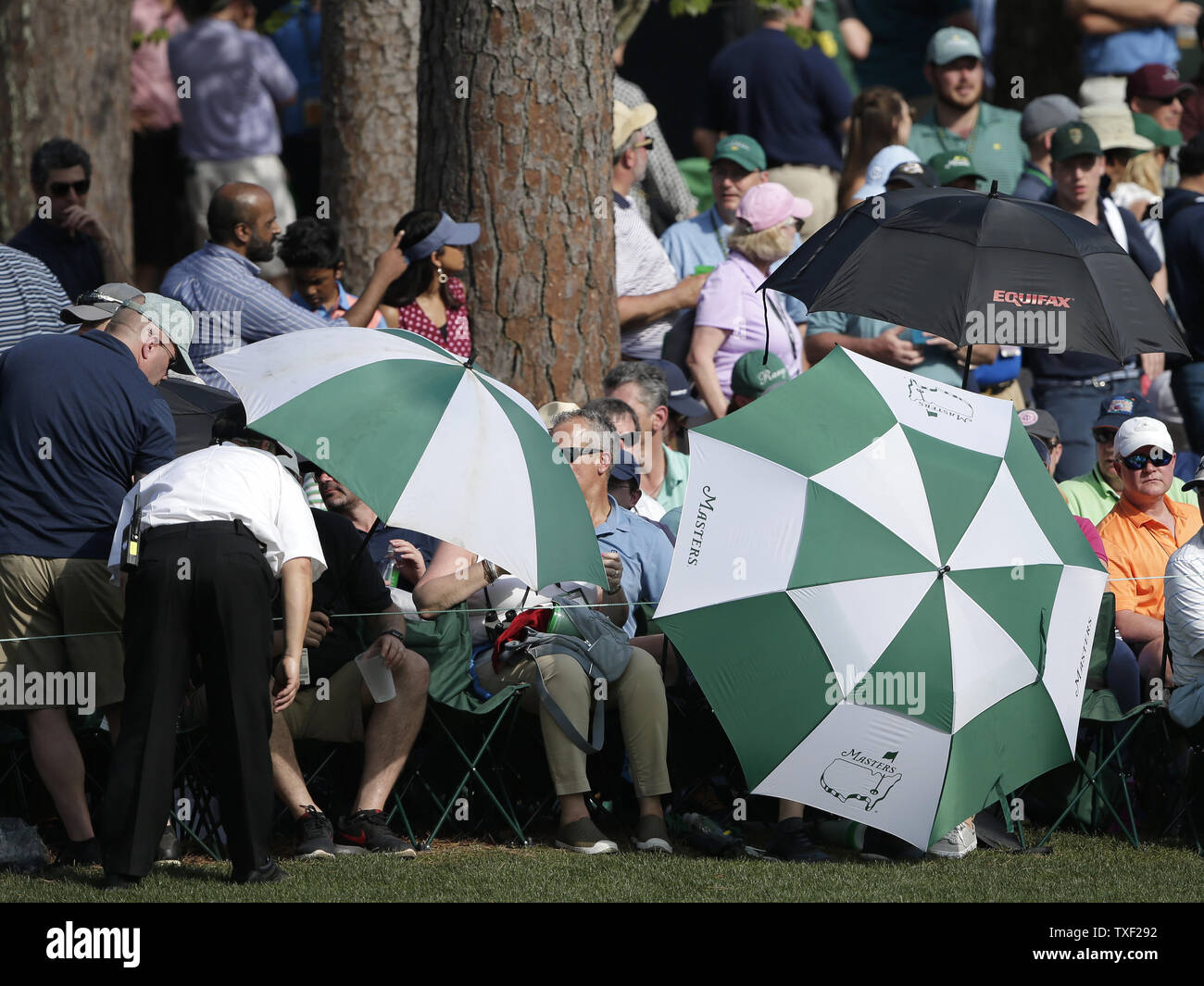 Patrons hold umbrellas to block sunlight on the 16th hole in the third