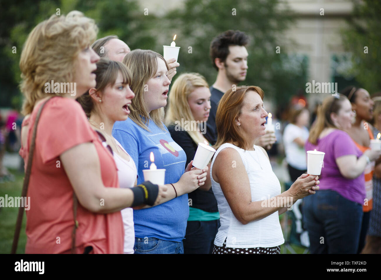 Megan Saunders (blue shirt) sings Amazing Grace with her friends and family during prayer vigil at the Aurora Municipal Center on July 22, 2012 to honor the victims of last Friday's movie theater mass shooting at the Century 16 Movie theater complex in Aurora, Colorado.  Saunders was in theater 9 at the time of the shooting.  Suspect James Holmes, 24, allegedly went on a shooting spree, killing 12 people and injuring 58 during an early morning premier screening of 'The Dark Knight Rises.'  UPI/Trevor Brown, Jr. Stock Photo