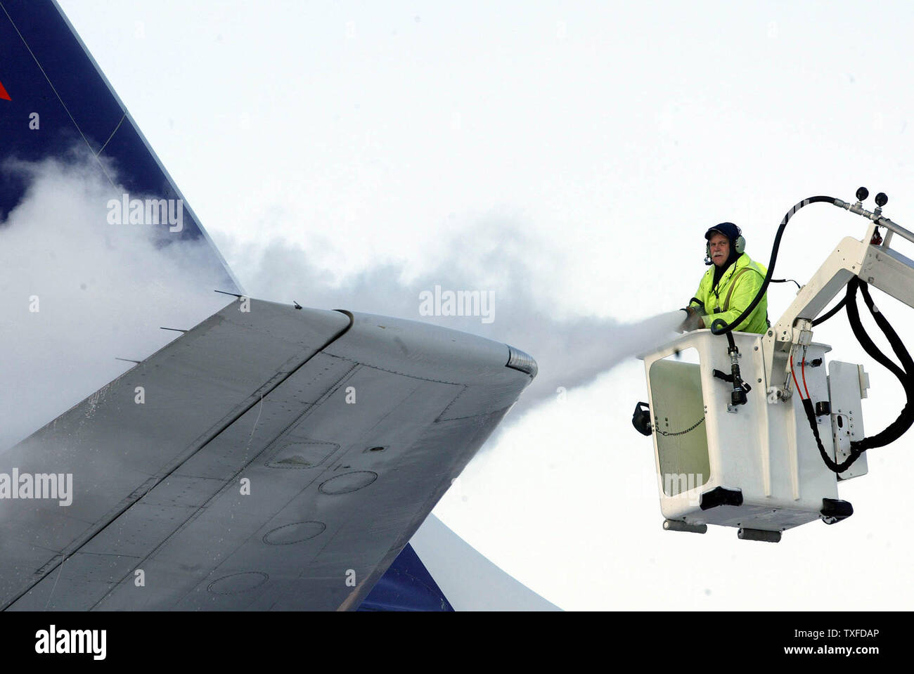 A ground crew deicer sprays deicing solution onto the tail of Federal Express aircraft, before it takes off from Bradley International Airport, in -7 c temperatures, as a heavy winter story tapers off, after dumping up to 18" of snow in the region, Sunday, December 7, 2003, Windsor Locks, Conn. The winter storm stranded many passengers throughout the East coast as flights were delayed or canceled due to the weather conditions. (UPI Photo / Steven E. Frischling) Stock Photo