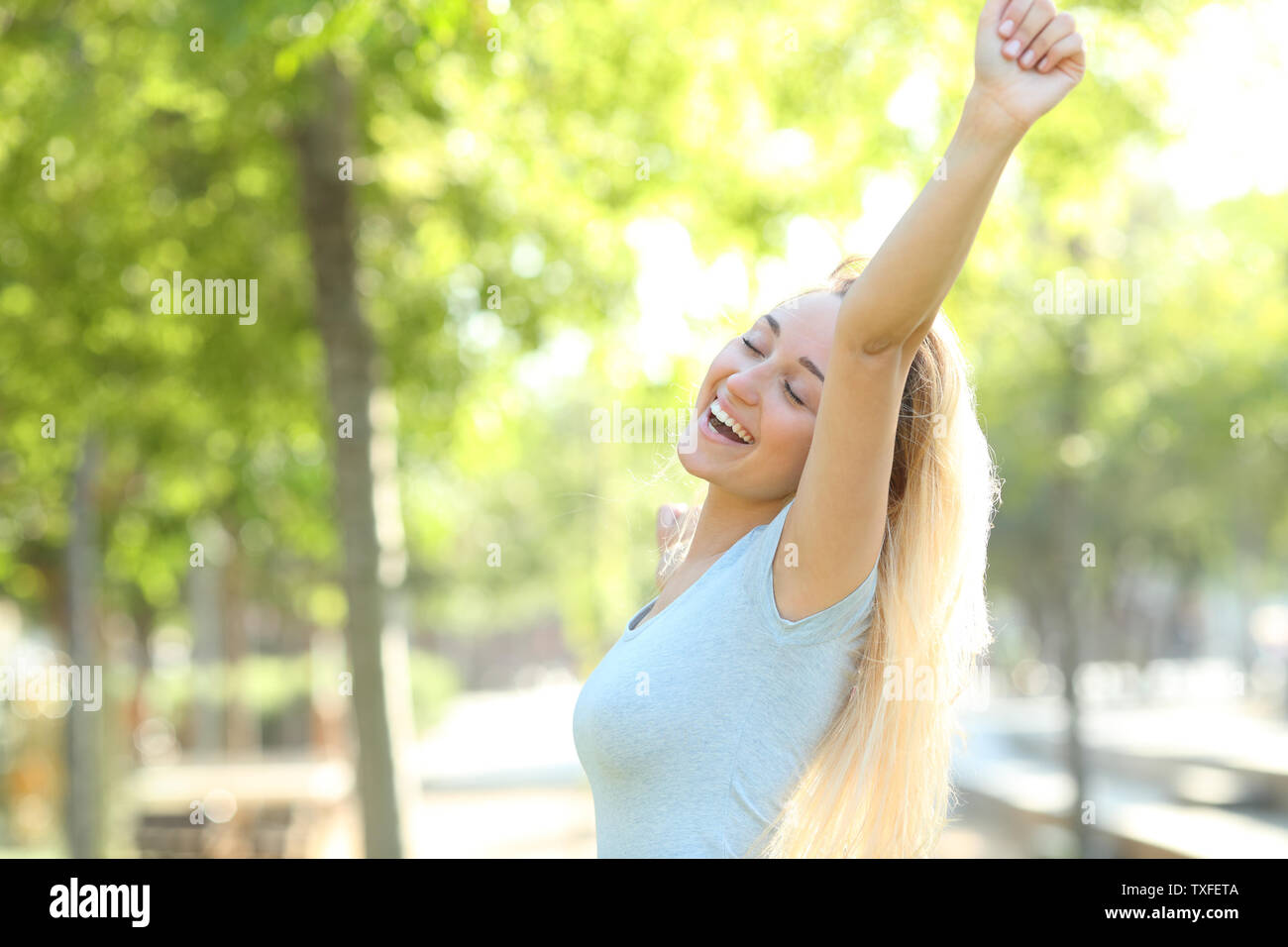 Happy teenage girl raising arms standing in a park Stock Photo - Alamy